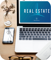 A laptop displaying "Real Estate" on a blue screen sits on a desk with a smartphone, reading glasses, and a small vase of dried flowers nearby. Professional tone.